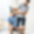 Man on exercise ball lifts dumbbell with therapist's assistance. Bright room, focused expressions, casual attire, rehabilitation setting.