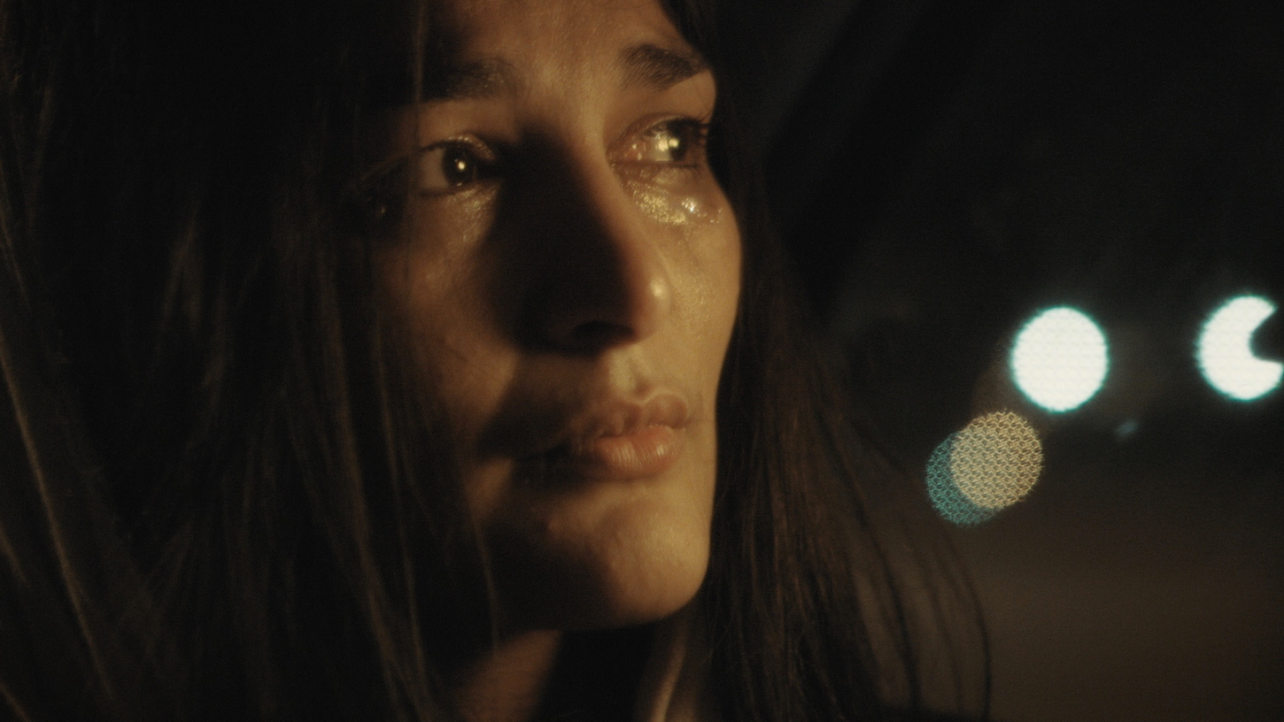 Dans une voiture, de nuit, une femme voilée verse une larme dans une voiture de nuit.