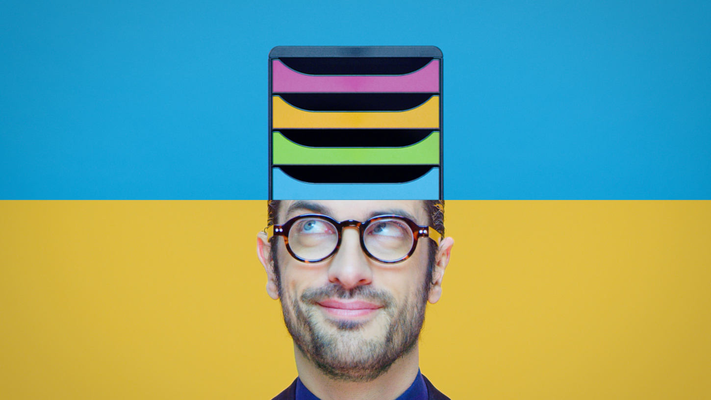 Un homme à lunettes observe un trieur coloré sortir du haut de sa tête.