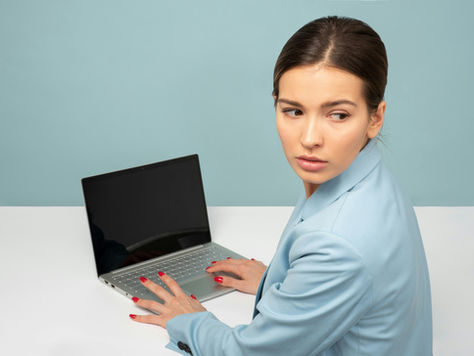 Woman on laptop looking over her shoulder unsure