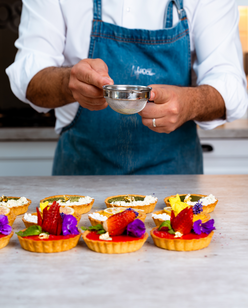 Chef dusting powdered sugar on handcrafted French tarts