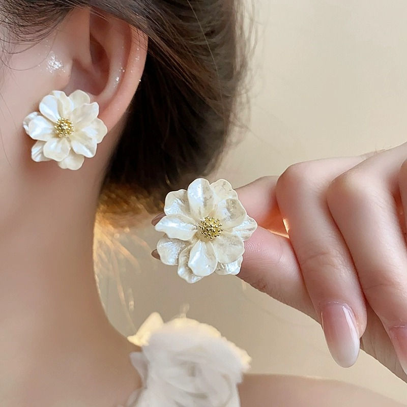 Thumbnail: White floral stud earrings worn on a model