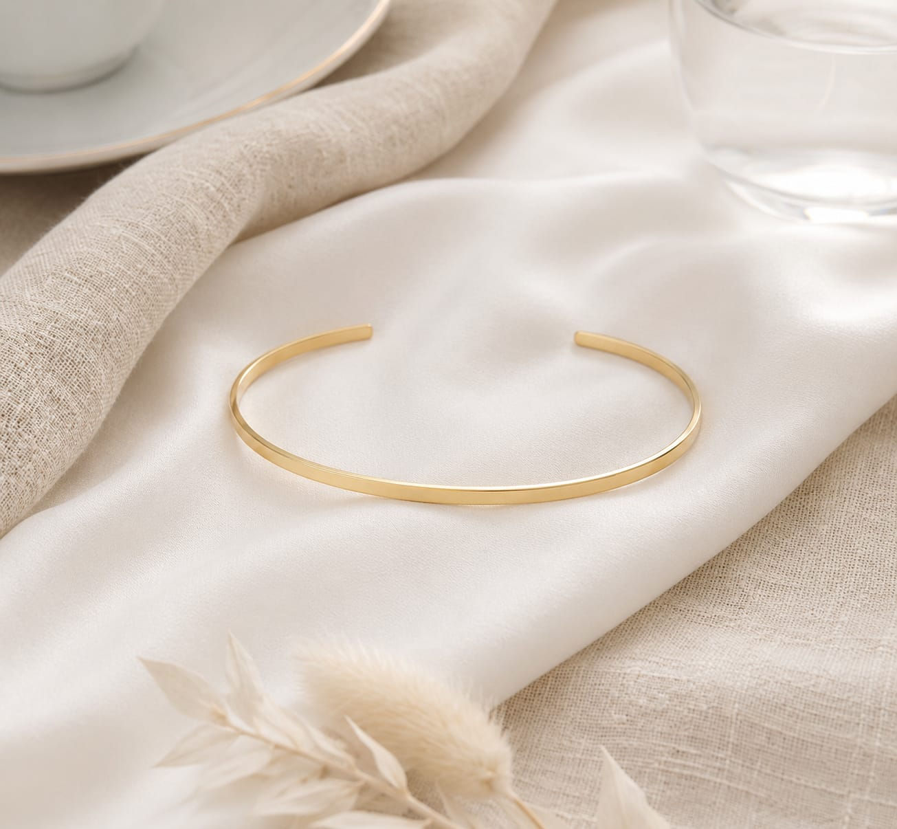 Gold cuff bracelet on draped white silk fabric