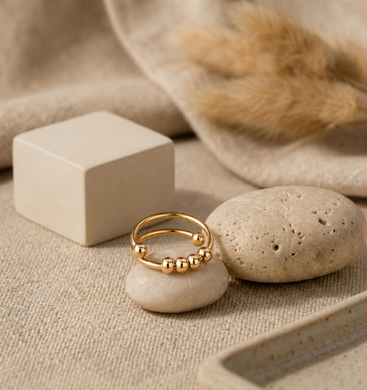 Gold Darling Cherry Drop fidget ring on a smooth stone.