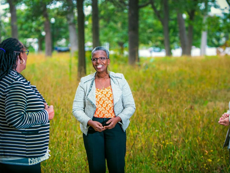 Claudette stands in a field with two IHP participants.