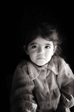 Portrait en noir et blanc sur fond noir d'une petite fille