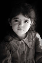 Portrait en noir et blanc sur fond noir d'une petite fille