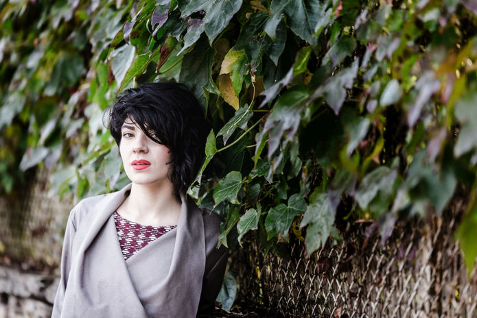 Portrait d'une jeune femme à la lumière d'automne posée contre une haie de feuilles