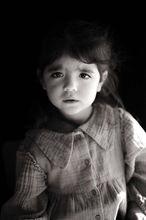 Portrait en noir et blanc sur fond noir d'une petite fille