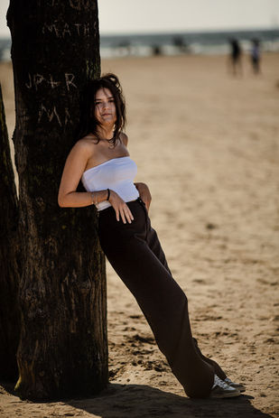 Jeune femme adossée contre un énorme poteau en bois sur une plage en été