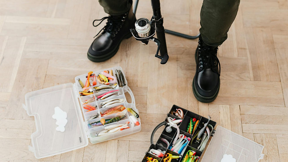 Fishing tackle boxes with lures and equipment beside boots on a wooden floor.
