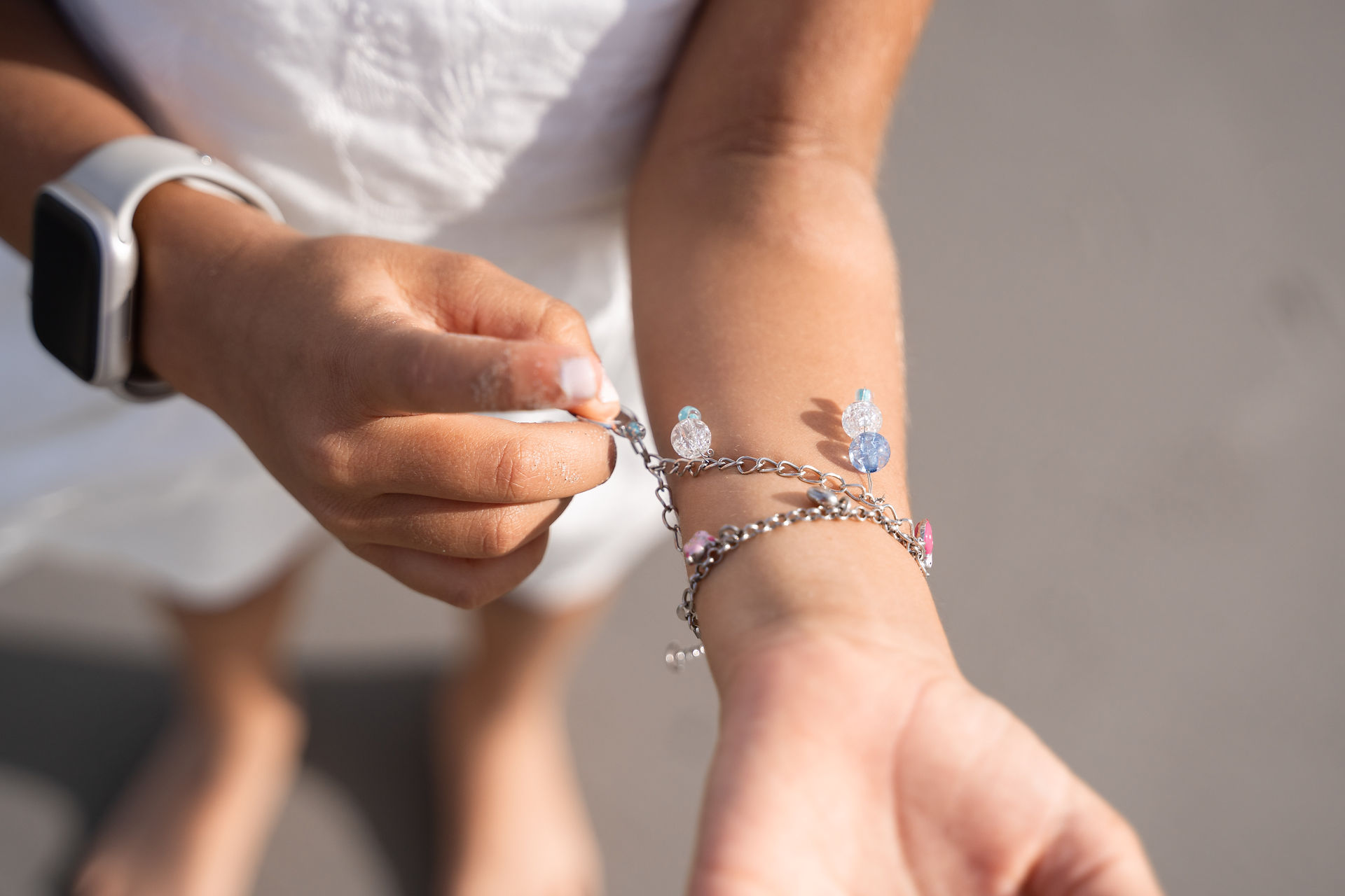 Detail van de dochter die trots haar armbandje met bedeltjes laat zien | Trouwfotograaf Ameland