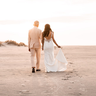 bruidspaar loop hand in hand op het strand van Ameland