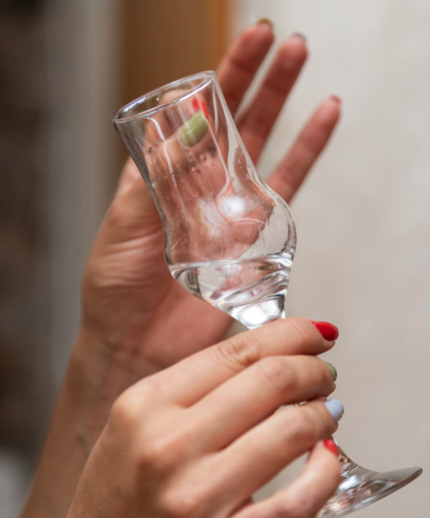 Hand holds a mezcal cup on a professional mezcal tasting explanation.