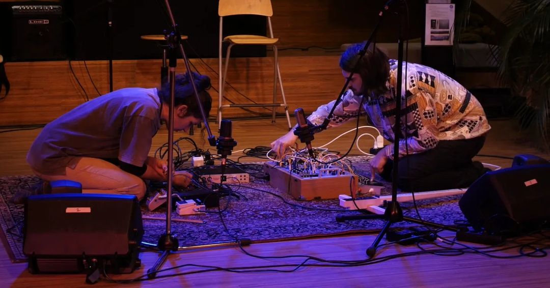 Two artists playing a synthetizer on the ground