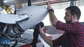 Bearded man polishing airplane propeller