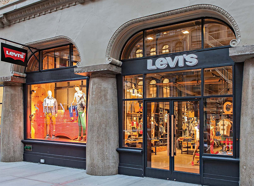 Levi's store exterior with mannequins in colorful outfits displayed in windows. Bold "Levi's" sign above entrance. Classic architecture.