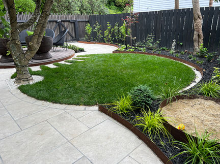 Contemporary back garden design with circular lawn and porcelain tile arranged in an ashlar pattern