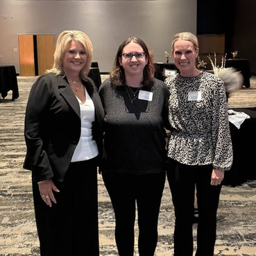 Three women smiling at an annual meeting event.
