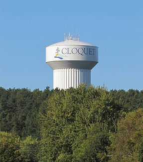 Cloquet water tower rising above a lush green forest line.