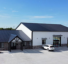 Exterior view of a white building with black roof and car parked.