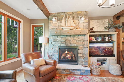 Custom home build featuring barn wood tongue & groove, timber beams, cabinetry, siding, trim, fireplace, and detailed timber frame entry in the interior design.