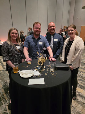 Four attendees smiling at a table at the Annual Meeting.