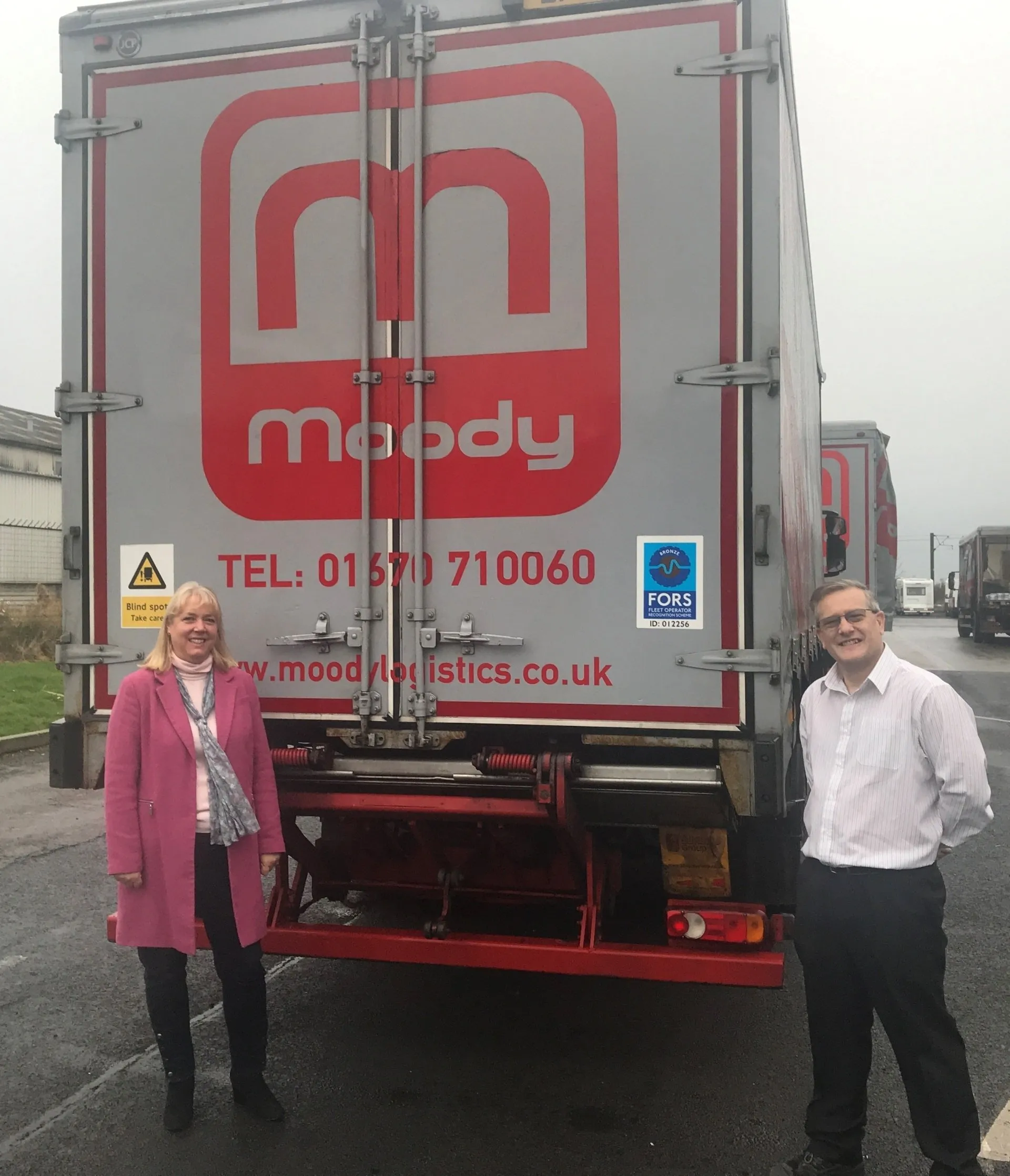 Man and lady standing at the back of HGV truck