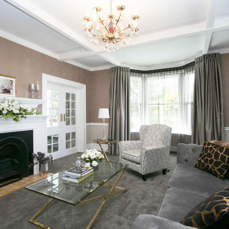 Elegant living room with white fireplace, grey sofa, and bay window