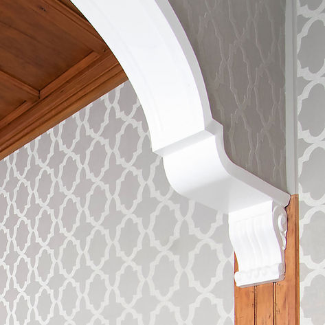 Elegant white archway trim with patterned wallpaper
