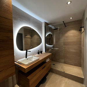 Salle de bain moderne avec meuble vasque en bois suspendu, miroir organique rétroéclairé et douche à l'italienne