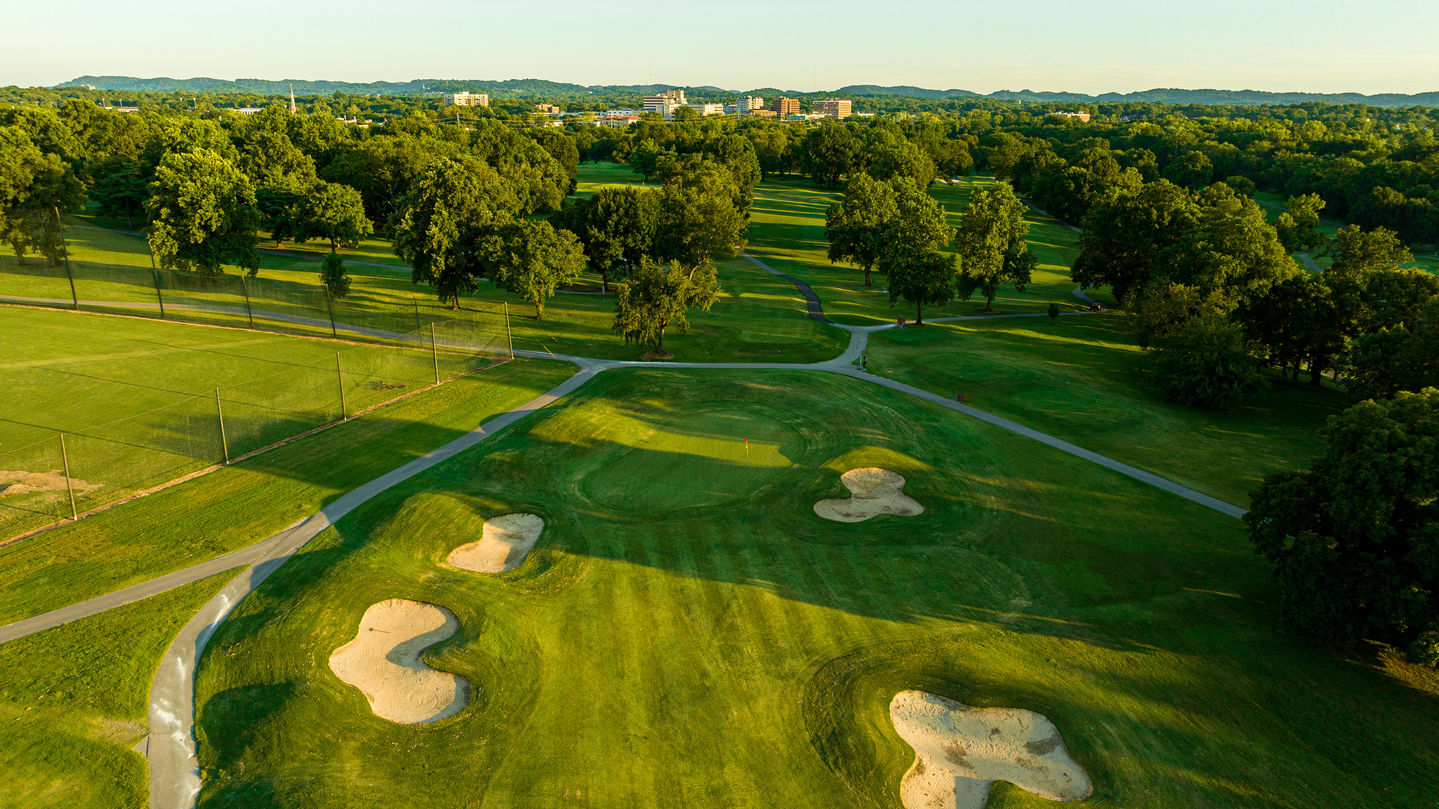an aerial view of a golf course with a city in the background