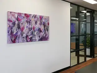 Abstract purple painting exhibits on a white office wall.
