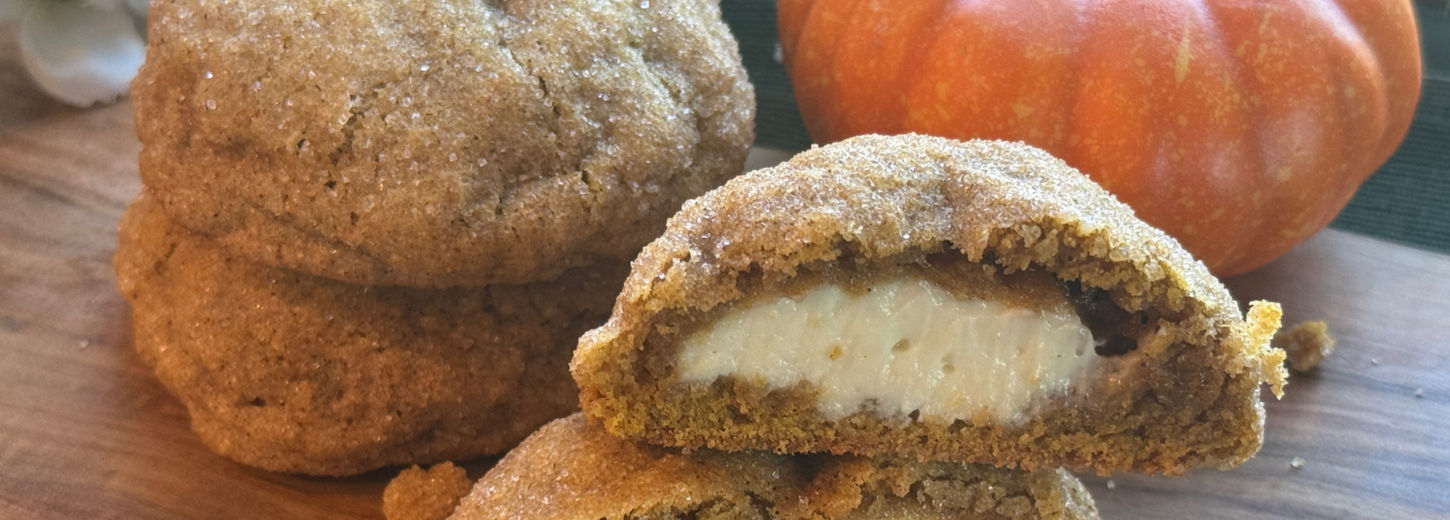 two pumpkin cheese cake cookies and one cookie broken in half.