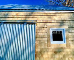 closeup of the corrugated metal shutter on the cedar-shingled cottage