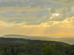 sun shining through clouds over the ocean