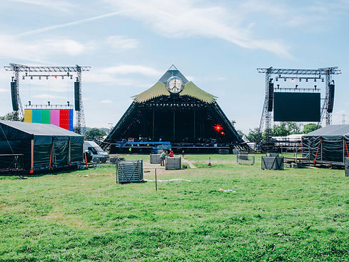 A wide shot of an empty stage and field at the Glastonbury music festival.