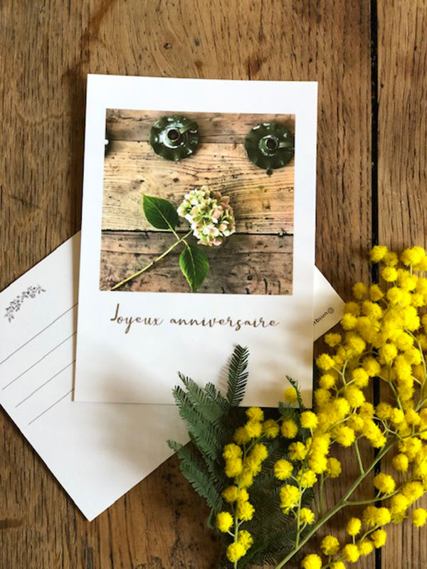 Carte postale avec fleurs, texte manuscrit, fleurs jaunes et arrière-plan rustique.