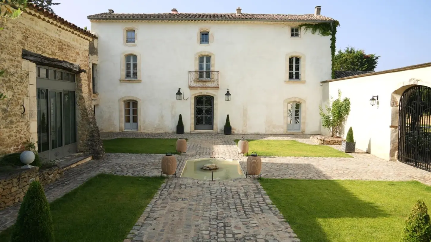 Façade et cour pavée de la Maison Yomana avec son portail en fer, à Oppède