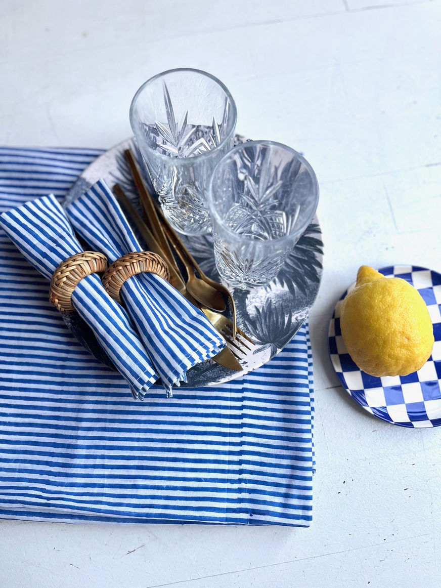 Table setting with blue napkins, lemon, and glasses. Unique en son genre.