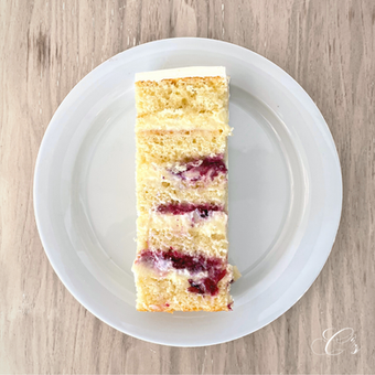 aufgescnittene Torte mit sichtbaren Layers von Zitronenbiscuit mit Creme-Belga Füllung durchsetzt mit Beeren