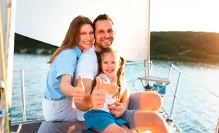 Happy family enjoying a sailing trip, giving thumbs up on a sunny day by the water.