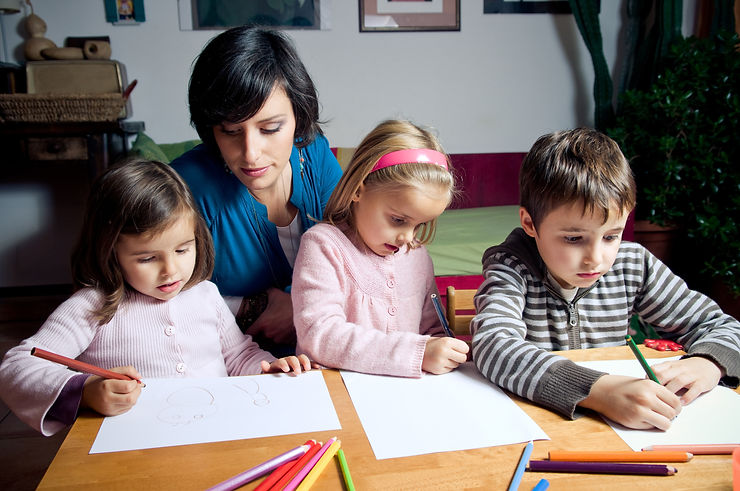 a mother and 3 younger children drawing with markers together