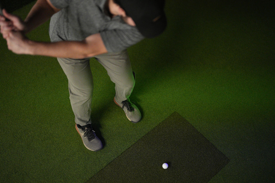 Golfer swinging at Simulinks Indoor Golf.