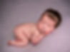 Photo of newborn girl laying on tummy with head on her hand on a lilac backdrop wearing sparkly headband by Specialist Newborn Photographer, Hull and East Yorkshire and North Lincolnshire