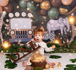 Photo of red haired by holding wooden "one" sign in front of jungle backdrop in 1st Birthday Cake Smash Photoshoot East Yorkshire, Hull and North Lincolnshire.