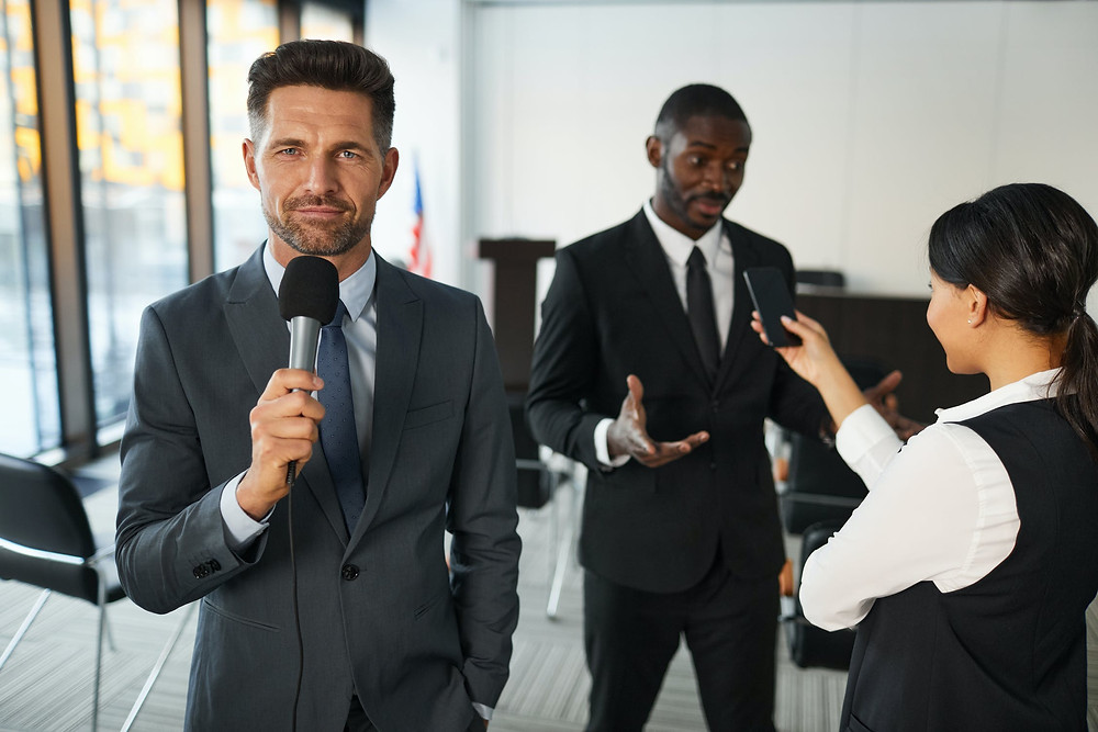 People in suits doing an interview indoors.