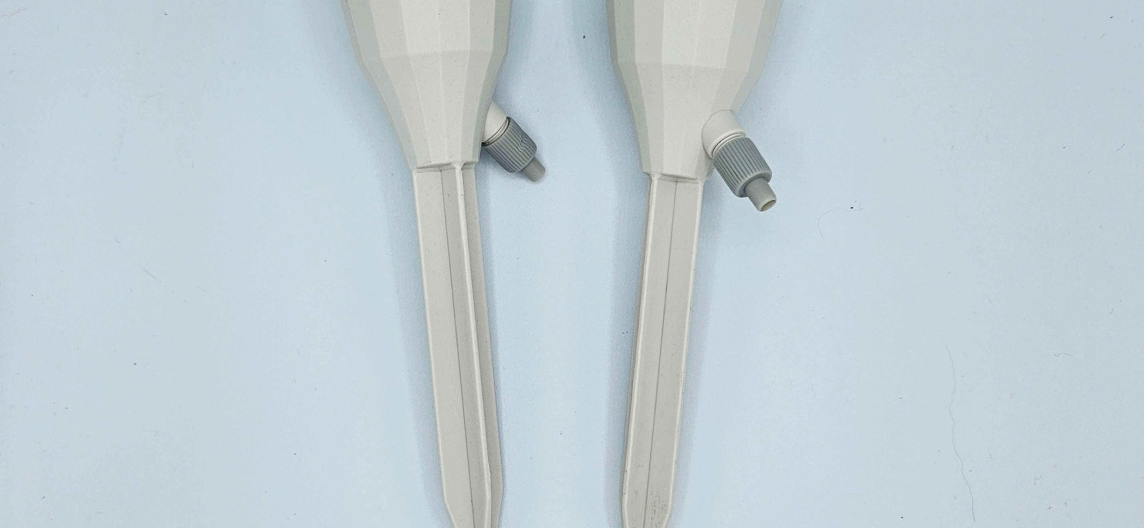 Two white Plant Waterers, side angle view. G
rey spigots coming out