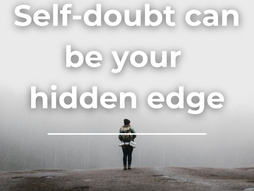 Photo of a person standing on the edge of a cliff looking out into an abyss of fog