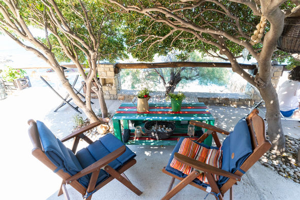 Small shaded sitting area under the Angeliki tree with sea view at Ikarian Endless Blue in Ikaria, Greece.